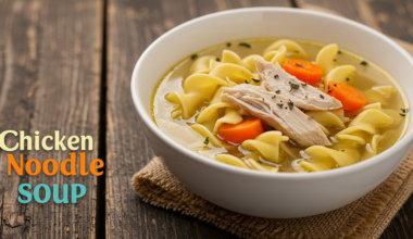 Close-up of chicken noodle soup in a rustic bowl with fresh herbs.